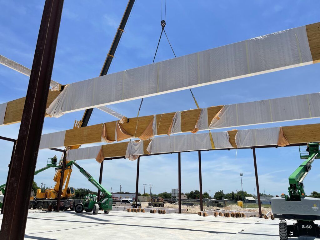 | binkley construction A close up of fire treated glulam beams being installed for a high school building.