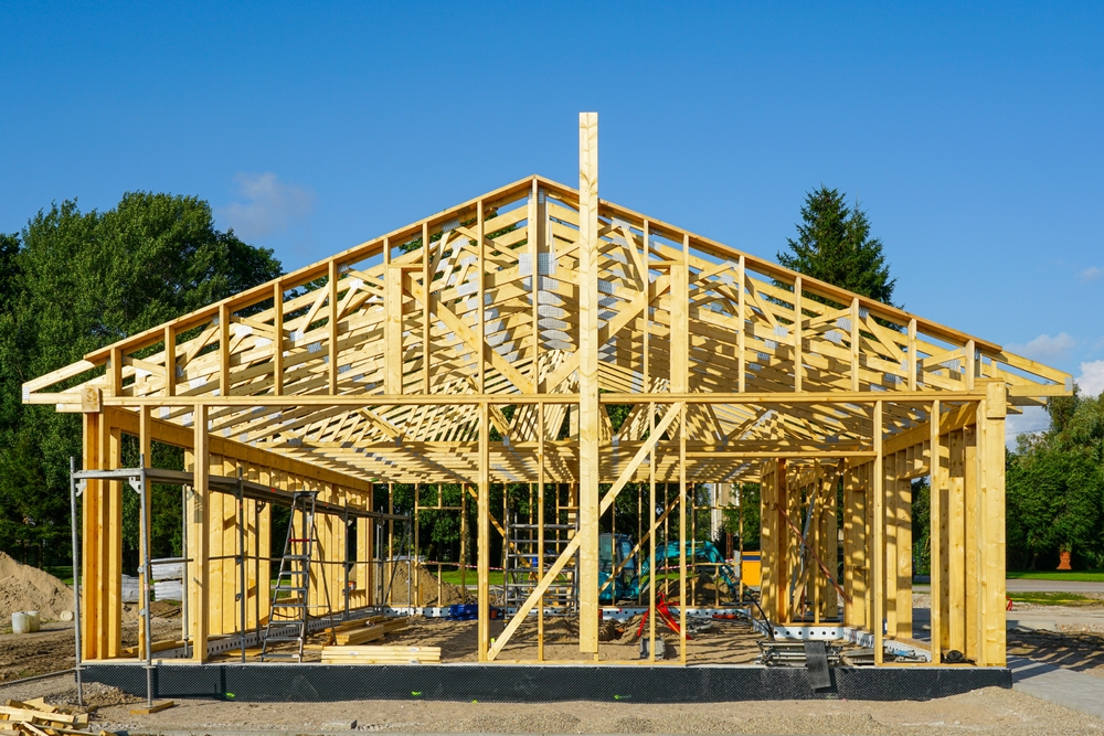 Exposed wooden house frame showing trusses and beams during early-stage construction.