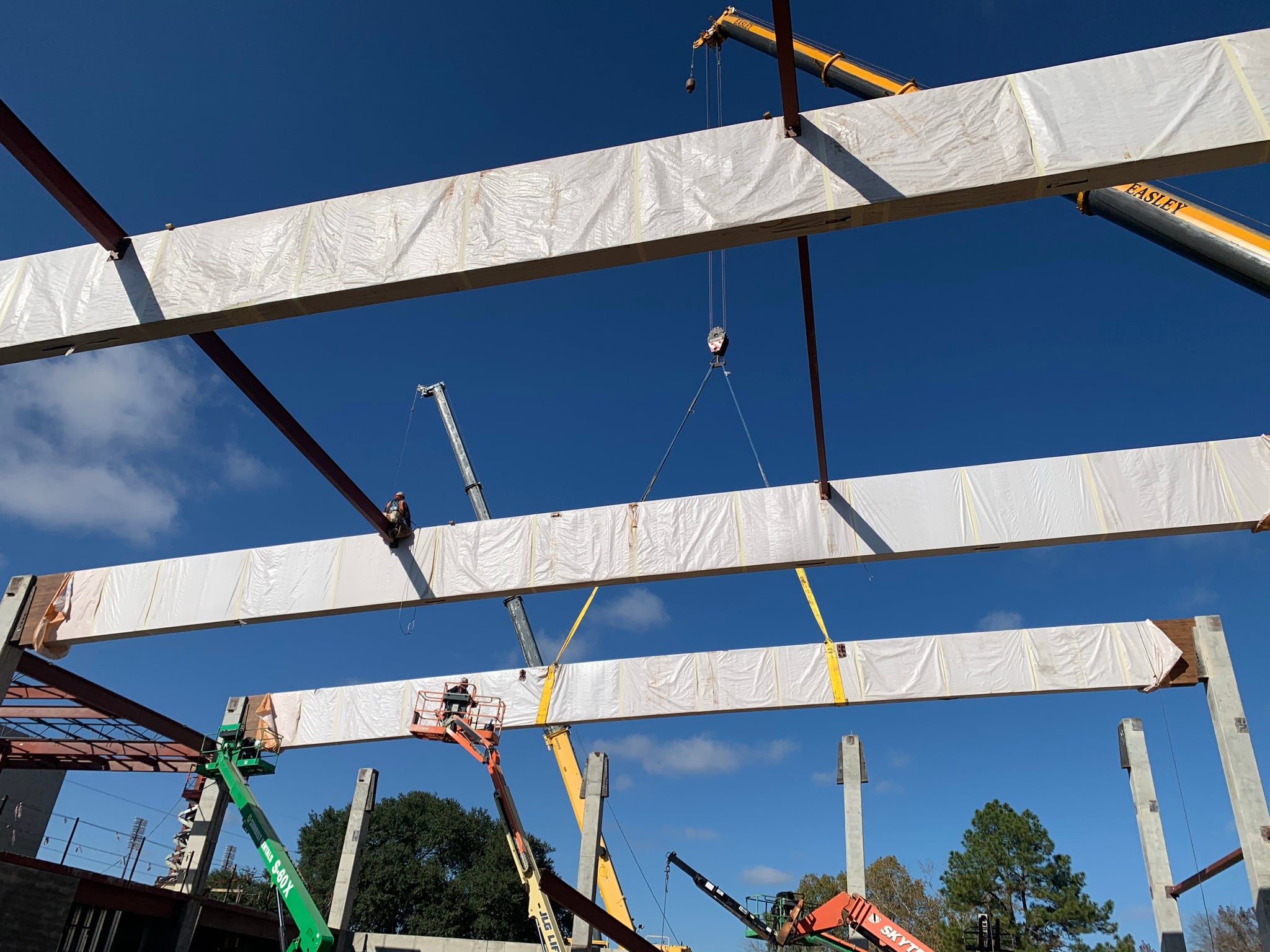 Timber beam being lifted into position by crane during structural timber erection on a construction site.